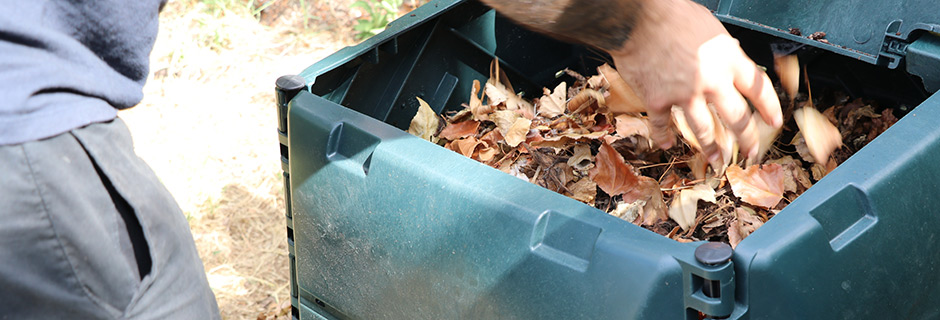 Un homme ajoutant des feuilles sèches dans un composteur en plastique vert (c) Bordeaux Métropole